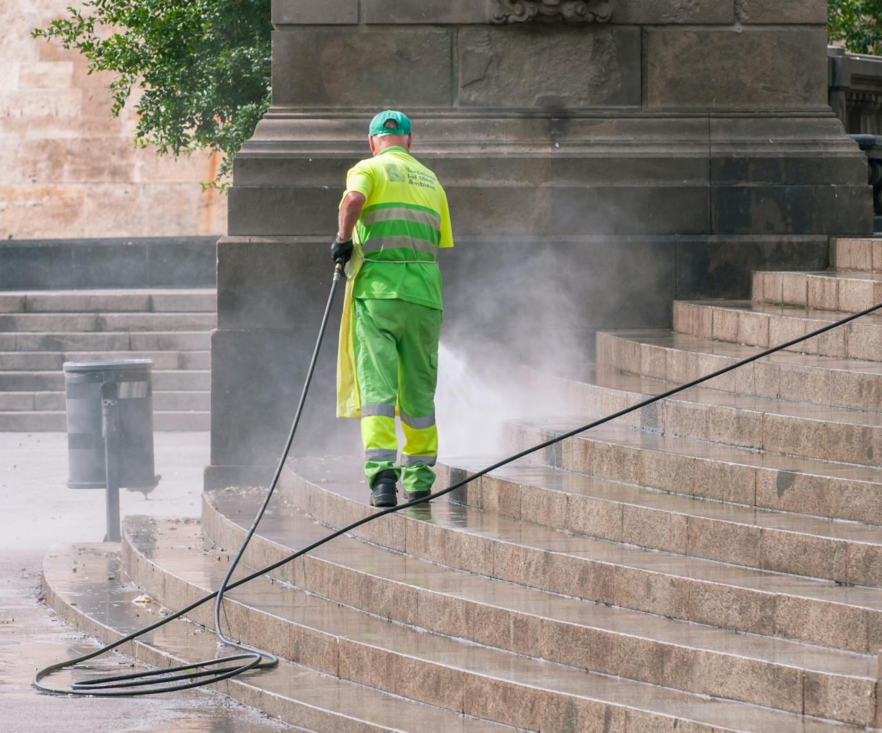 services-04 A municipal worker power washing stone steps outdoors, ensuring cleanliness and maintenance.